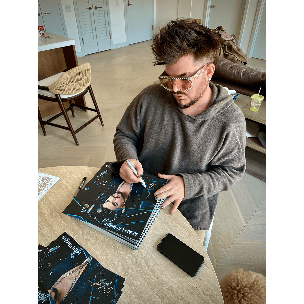 Adam Lambert signing the art cards for the limited edition crystal clear vinyl LP of High Drama